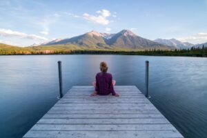 Woman sitting on dock looking out at water - calm and reflective.